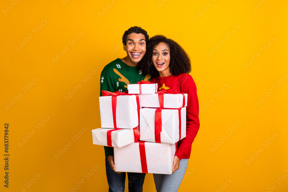 Sticker portrait of two astonished positive people hold big pile stack x-mas giftbox isolated on yellow colo