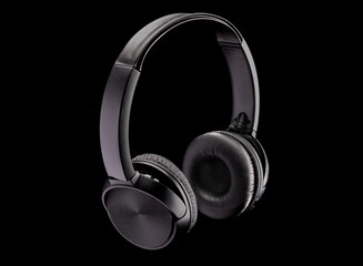 Fototapeta na wymiar A pair of black bluetooth wireless headphones on a black background