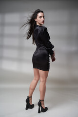 Glamour lady in tight mini black dress on gray