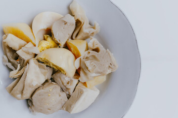 Close up of Siomay Bandung or steamed dumplings, traditional Indonesian street snacks without peanut sauce and soy sauce, served on a white plate. Copy space. Indonesian culinary food concept.