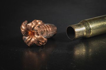 Expansive crumpled 308 caliber bullet and spent cartridge case, macro photo.