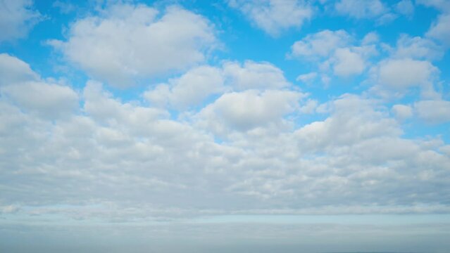 Clouds, like white brush strokes on the bright blue canvas of the sky, create a beautiful cloudscape, time lapse.