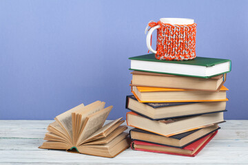 Book stacking. Open book, hardback books on wooden table and blue background. Back to school. Copy space for text.