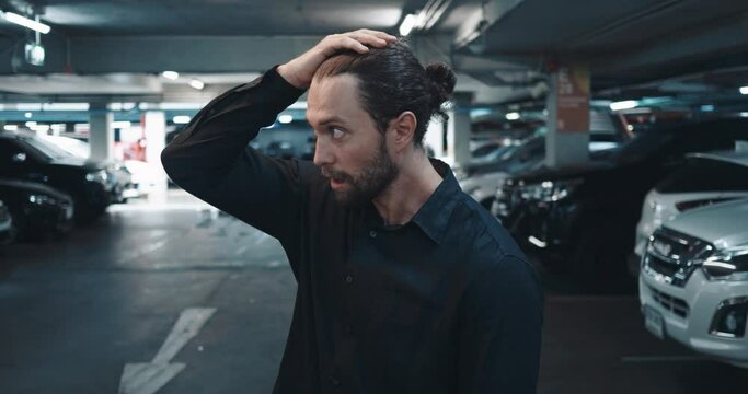 In crowded parking lot, man inspects wrecked car, his face expressing deep frustration. Emotions explode as guy surveys damage wrecked car. Concept reality of difficult aspects of car ownership.