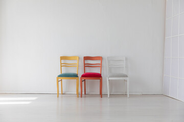 Three colorful vintage chairs in white room interior