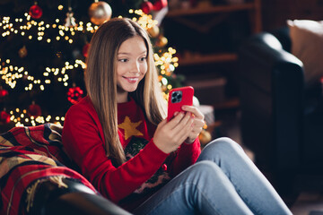 Photo of smiling girl teenager surfing social networks cellphone using new features her iphone she received surprise in new year indoors