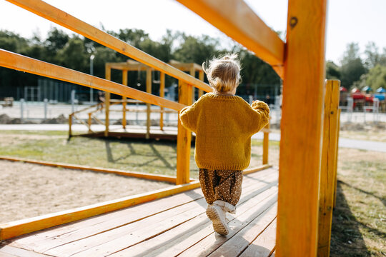 Child running on a wooden bridge at a playground outdoors. - Powered by Adobe