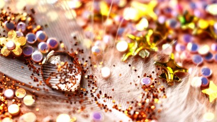 water drops on a feather with glitter around it in colorful light