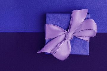 Blue gift box with a purple bow on a two-tone background, blue and purple.