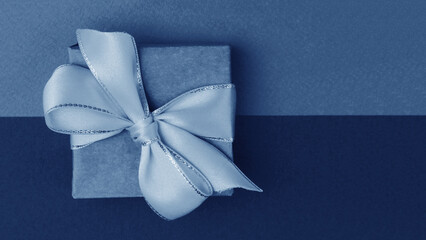 Blue gift box with white bow on blue green background.