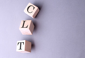 Word CLT on wooden block on the grey background