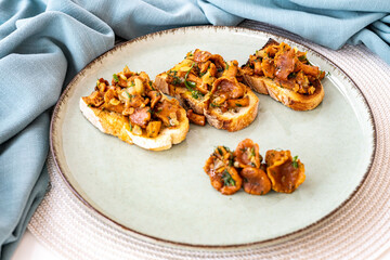 Bruschetta with pan fried chanterelle mushrooms with olive oil, onion, garlic, and dill on a green ceramic plate. Home cooking, eating healthy.  Italian dish. Closeup of vegetarian dish