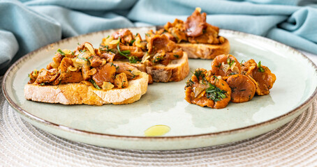 Bruschetta with pan fried chanterelle mushrooms with olive oil, onion, garlic, and dill on a green ceramic plate. Home cooking, eating healthy.  Italian dish. Closeup of vegetarian dish
