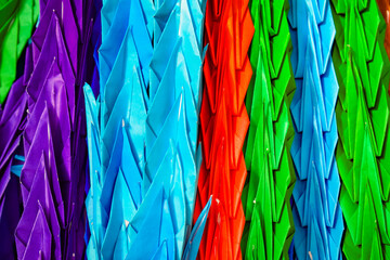 Strings of colourful folded origami paper cranes in Hiroshima peace park, Japan. If you fold a 1000...