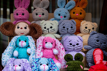 Soft handmade knitted toys stand on shelves for sale