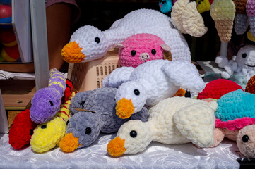 Soft handmade knitted toys stand on shelves for sale