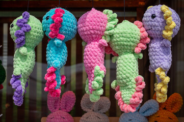 Soft handmade knitted toys stand on shelves for sale