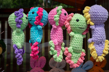 Soft handmade knitted toys stand on shelves for sale