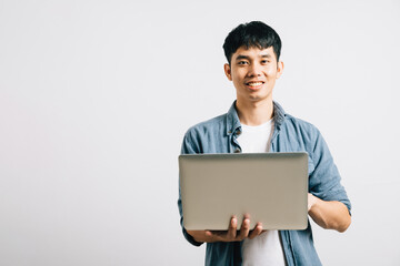 Portrait of a man with a confident smile, typing on a laptop for a successful email or chat session. Studio shot of Asian student isolated on white, showcasing his proficiency in online communication.