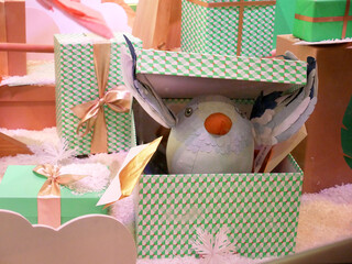 Christmas Gifts displayed in a decorated store window decorated . A soft toy chick opens a gift package