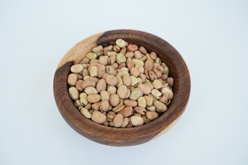 Dried fava beans on a wooden plate isolated on a white background
