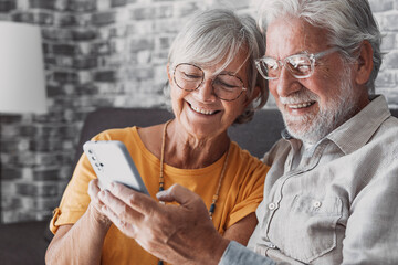 Elderly grandfather and grandmother spend time having fun using smartphone apps, middle-aged wife enjoy online entertainments, taking selfie with old husband, older generation and modern tech concept. - obrazy, fototapety, plakaty