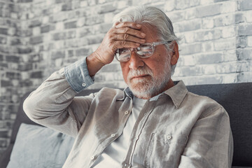 Frustrated unhealthy senior mature man touching head, having painful feelings sitting alone at...