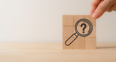 Magnifying glass and question mark icon on wooden cube blocks. Question mark, problems and root...