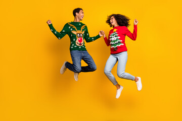 Fototapeta na wymiar Full length photo of two overjoyed ecstatic people hold hands jump raise fists christmas magic isolated on yellow color background