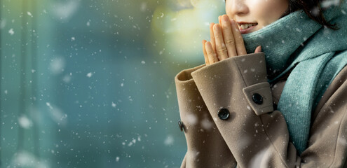 雪の降るクリスマスの街角に立つ笑顔の女性