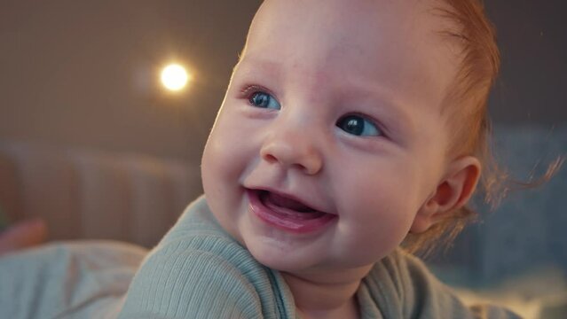 Close-up of joyful baby girl smiling indoors, a picture of early childhood happiness