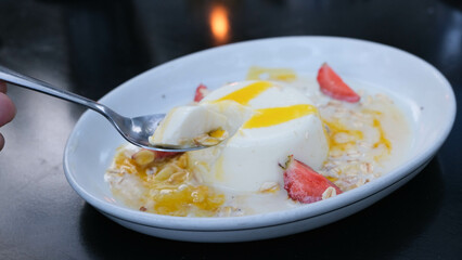 Creamy panna cotta topped with vibrant passion fruit and strawberry slices, perfect for dessert...