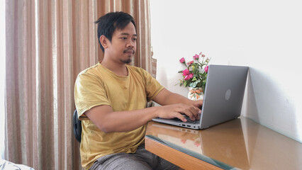 Concentrated man working from home with laptop in a cozy interior setting
