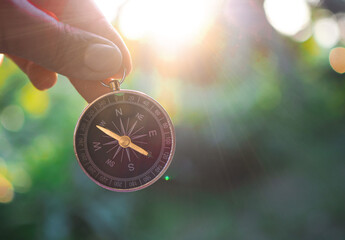Hand holding compass with nature background. The concept of world tourism day, Searching the right...