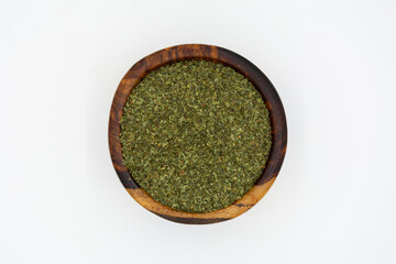 dried parsley in brown wooden plate on blue marble
