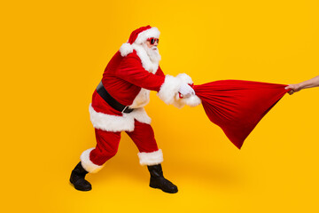 Full body profile photo of crazy santa pull fight person arm hold christmas bag isolated on yellow...
