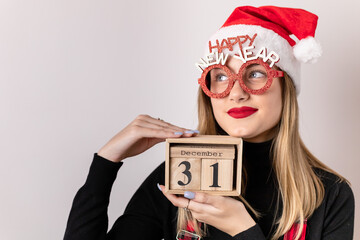 Girl with Santa hat holding a wooden calendar date box. December 31st