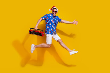 Fototapeta na wymiar Full size profile photo of cheerful handsome guy jump hold boombox have fun isolated on yellow color background