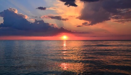 Obraz premium Heavy sunset under the sea with pink tones in the sky and reflection of sun on water surface, black clouds, bright orange-pink highlights