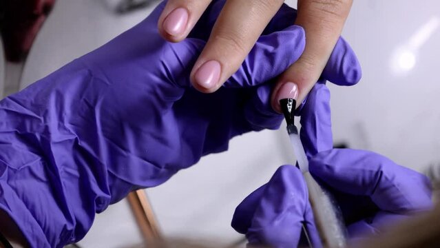A manicure teacher shows a student how to do a top coat application
