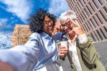 Happy multi-ethnic businesswomen taking a funny selfie outdoors