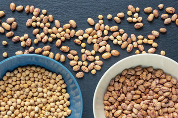 Sorting. Chickpeas and brown beans on black table. Sorting legumes by grade