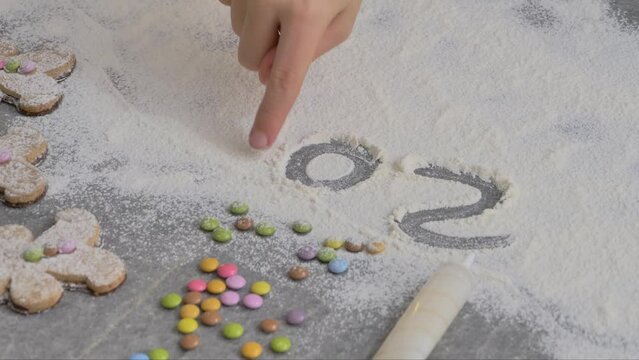 a child's hand draws 2024 in flour