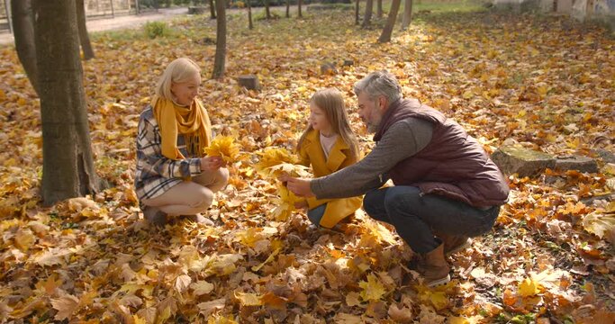 Small girl with grandparents on a walk in autumn forest