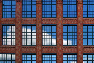 Blue sky and white clouds reflection in big glass windows in red brick walls