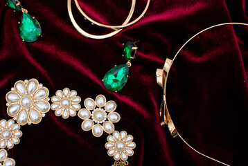 Flat lay photo of a christmas party outfit with gold and green earrings, jewelry, and pearl...