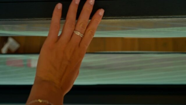 A close-up of a woman's hand grasping the doorknob and opening the glass door to the house