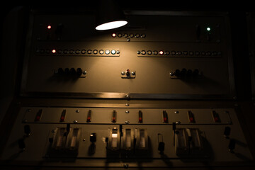 Antique control panel of a nuclear power plant is illuminated in the dark by a lamp. Vintage...