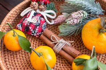 New Year's tangerines on the table with decorative Christmas trees. Festive atmosphere with white burning candles in the background