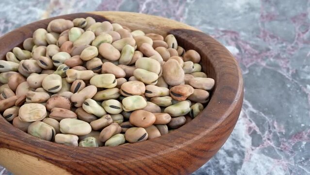 Dried fava beans in brown wooden plate on blue marble ,pan, close, HD, 24fps
